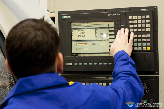 un homme travaille sur une machine outil en surveillant le panneau de contrôle dans l'atelier de mécanique générale admg51 dédié à la fabrication de pièces métalliques par usinage de précision